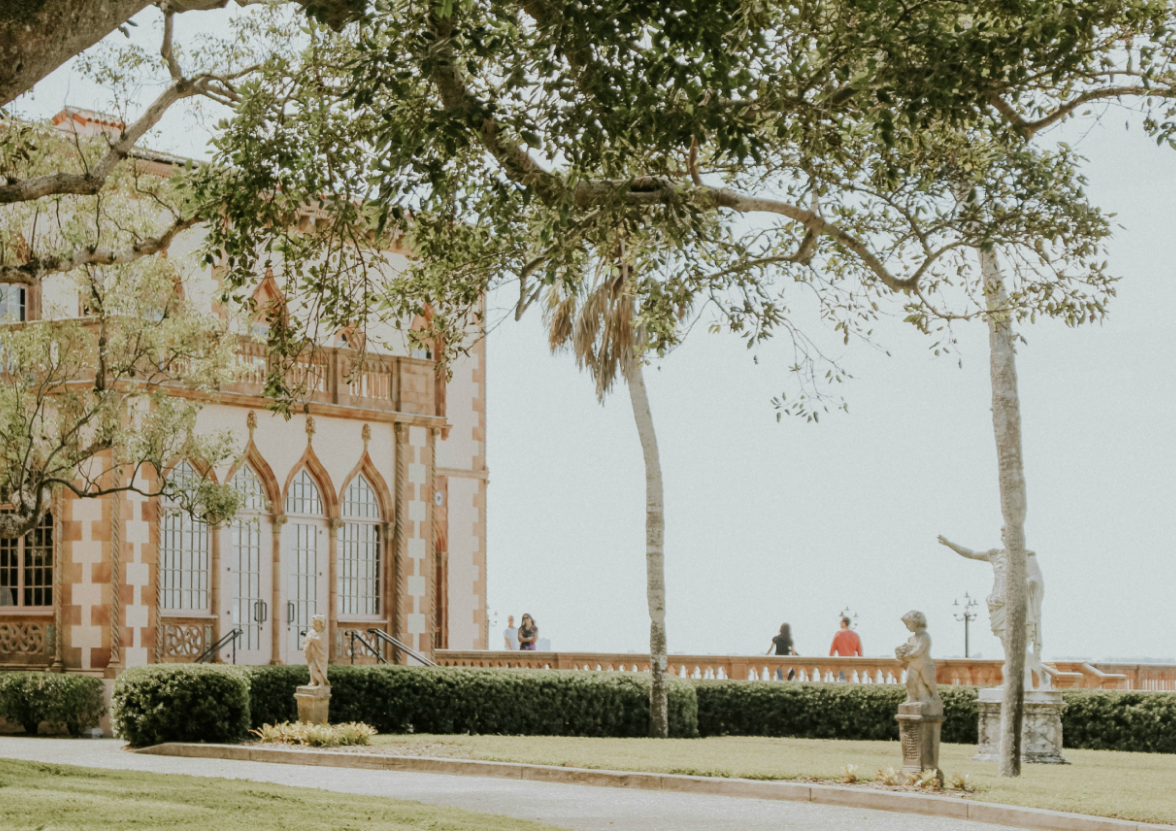 Green trees beside the brown building of Ringling Museum in Sarasota, Florida during daytime.