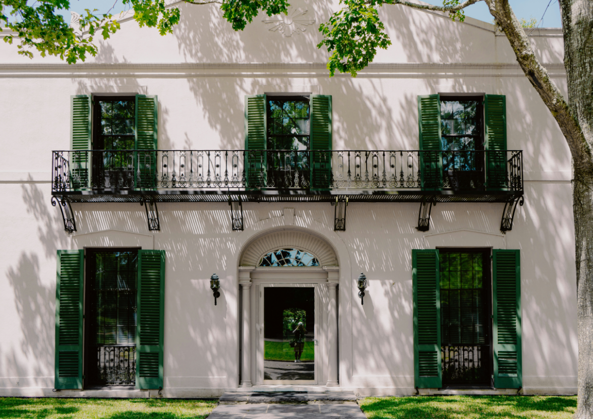 White concrete building nested in the Bayou Ben Collection and Gardens, a facility of the Museum of Fine Arts.