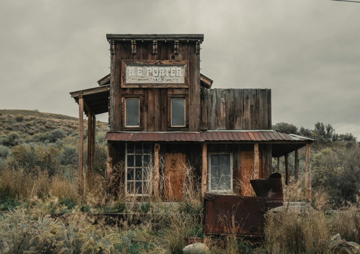 An old, run down, building sitting in the middle of a field.